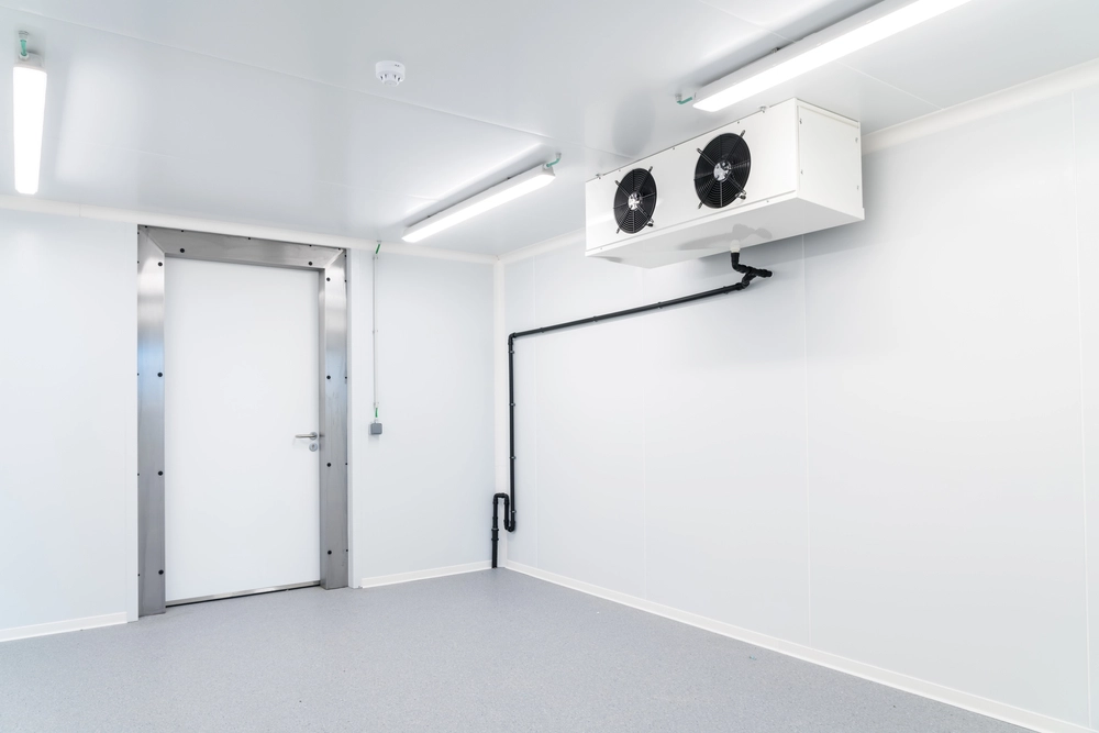 Refurbishment projects | Cold room installation experts. Pristine cold room with air conditioning unit and white walls with a stainless steel door frame.