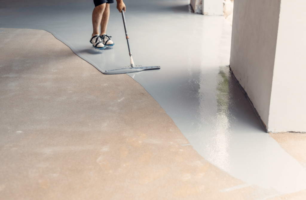 Resin flooring | Person laying down resin flooring onto hard concrete floor.