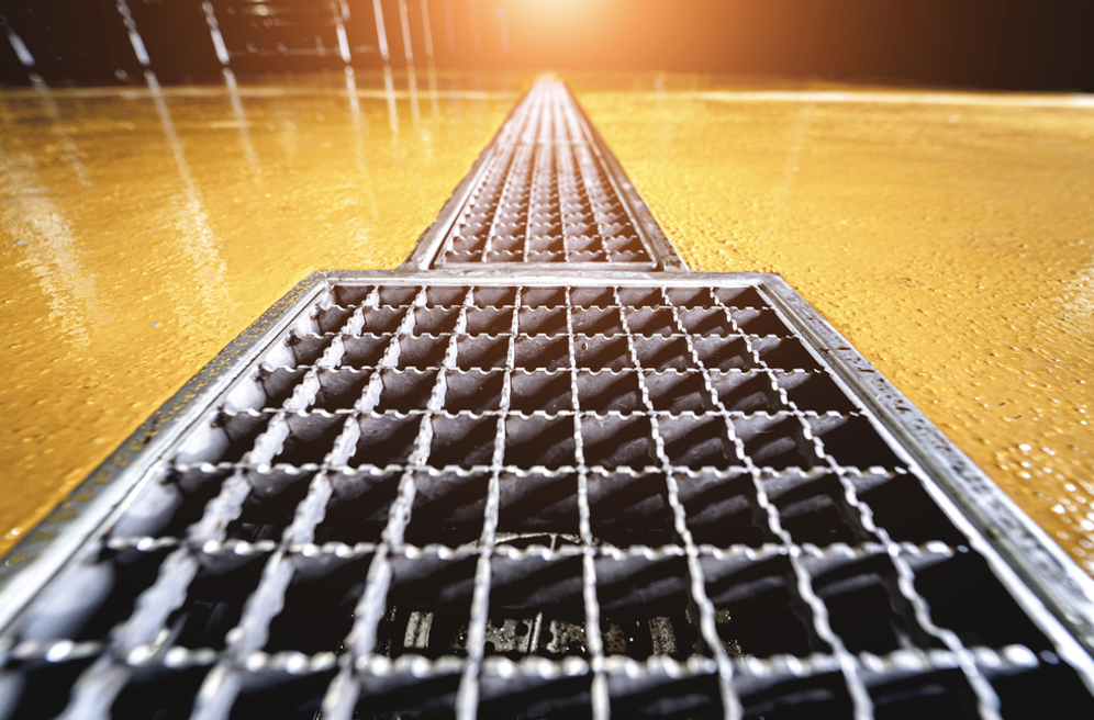Industrial drainage | Metal drainage grate on yellow resin floor.