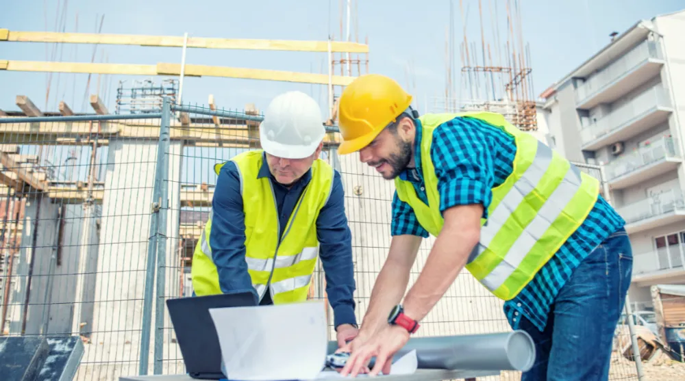 Construction project managers | people standing around building plans.